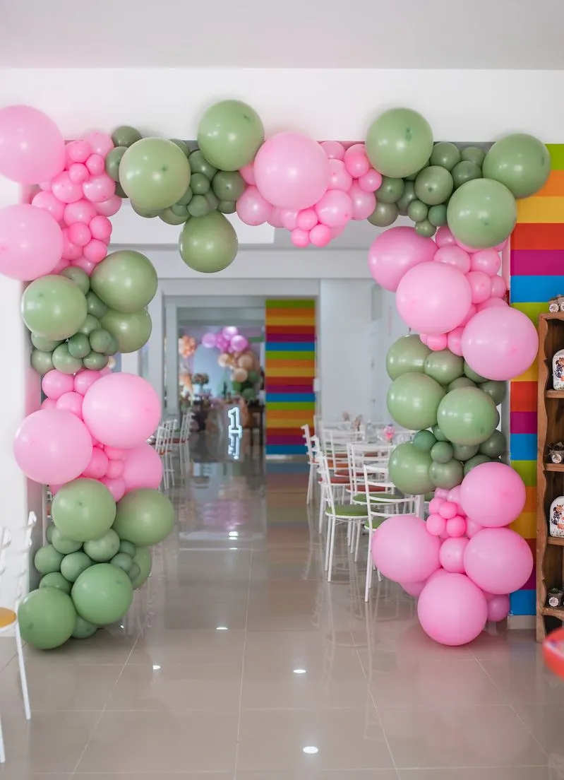 Arco de balões rosa e verde na entrada do salão