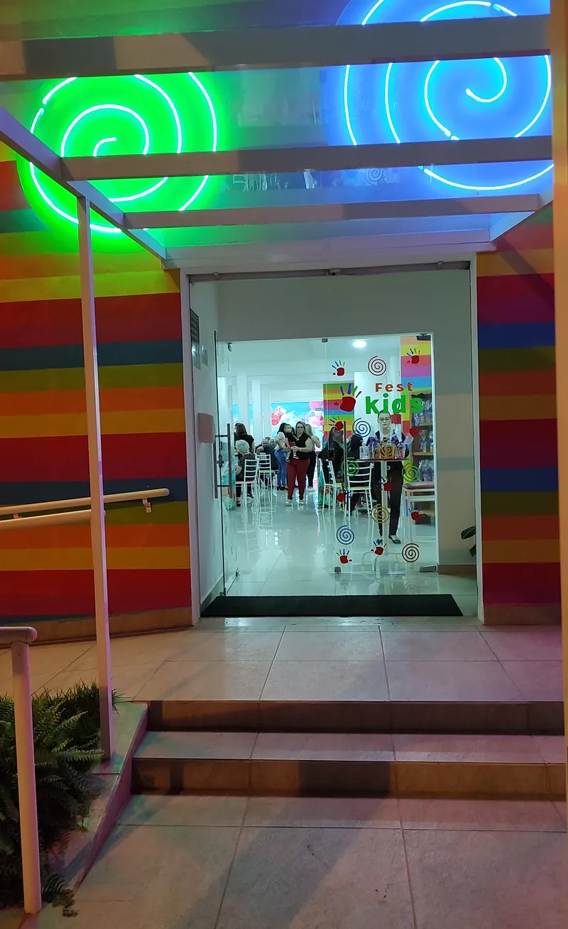 Entrada da Fest Kids com parede listrada colorida, espirais de neon e porta de vidro