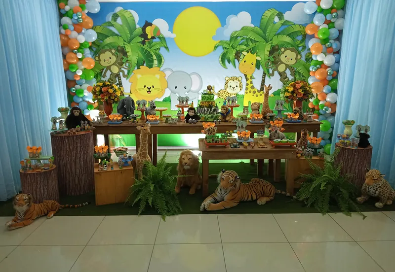Mesa com tema safári, painel de floresta e bichos de pelúcia sobre grama